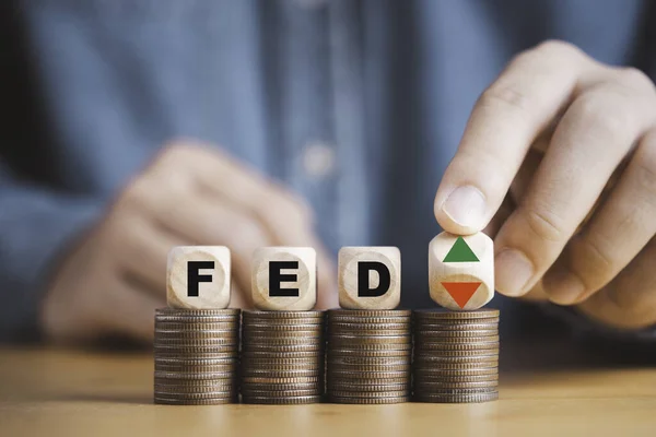 Businessman flipping up and down arrow with FED on coins stacking for Federal reserve increase and decrease interest rate control which effect to America and world economic growth concept.