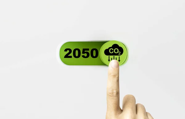 Hand touch to on and off green toggle switch button with CO2 reducing icon and 2050 number for decrease CO2 , carbon footprint and carbon credit to limit global warming from climate change concept.
