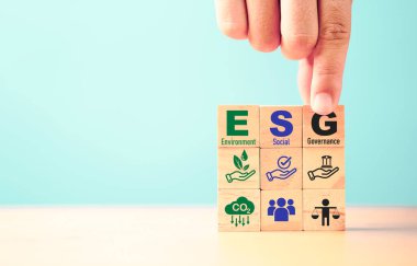 Businessman assemble ESG wording on wooden cube block for sustainable organization development and corporation of Environment Social Governance concept.  clipart