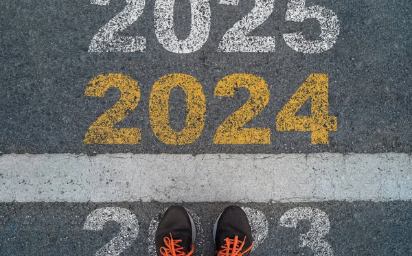 Runner standing on 2023 start point and next point is 2024 for preparation new year change and start new business target strategy concept.
