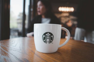 Seul, Güney Kore - 12 Nisan 2023 Starbuck kahve fincanını bulanık Starbuck kahve kafesi ve kadın arka planıyla kapatın, Starbucks dünyanın en büyük kahve servisidir..