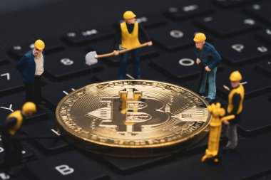 Madencilerin minyatür figürleri bilgisayar klavyesindeki altın bitcoin 'leri kripto para yatırımı için blok zinciri teknolojisiyle ticaret yapıyorlar.