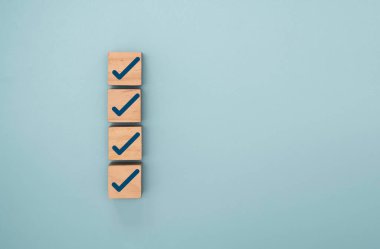 ISO kalite kontrolü ve ticari ürün konseptini onaylamak için kontrol listesi için tahta küp alanı olan mavi doğru işaret ve kene işaretleme işareti.