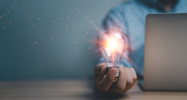 Problem çözme, patent ve yenilik kavramları hakkında yaratıcı düşünme fikrini aydınlatan parlak ampulü tutan el ele tutuşmak.