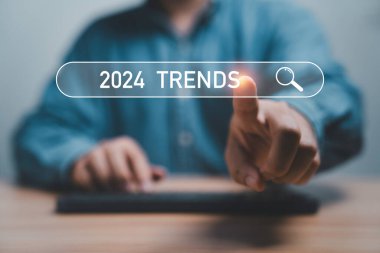 İş adamı, yeni yıl konseptinde pazarlama izleme ve iş planlama için 2024 trend içeren arama motoru çubuğuna dokunuyor.