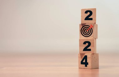 Yeni yıl değişikliğine hazırlanmak için tahta blok küpte hedef tahtası ve okla 2024 ve yeni iş hedefi stratejisi kavramı.