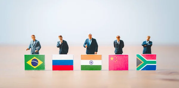 Businessmen miniature figure standing with Brazil Russia India China and South Africa flag for BRICS economic international cooperation and conference meeting concept .