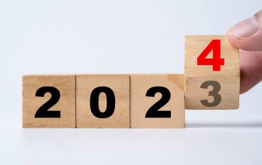 Hand flipping of 2023 to 2024 on wooden block cube for preparation new year change and start new business target strategy concept.