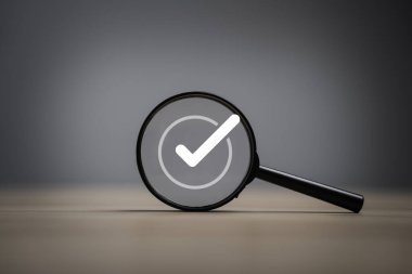 Belge ve proje onayı için siyah büyüteç içinde beyaz doğru işaret sembolü, ISO kalite güvence kontrol kavramı.