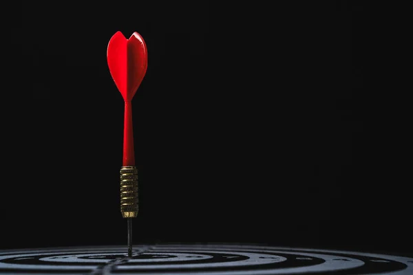 Red arrow shoot to dartboard on dark background for setup business objective target and goal concept.