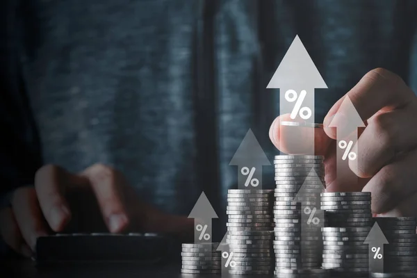 Hand stacking heap of coins money with up arrow and percentage symbol for financial banking increase interest rate or mortgage investment dividend from business growth concept.