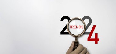 2024 yılına ait el ele tutuşan büyüteç ve 2024 iş pazarlama eğilimleri ve planlama değişikliği kavramına odaklanma eğilimleri.