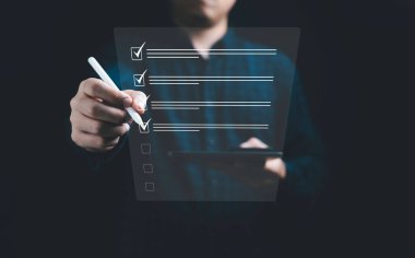 ISO konseptinin kalite kontrol güvencesi için çevrimiçi belge kontrol listesinde işaretlemek için elektronik kalem kullanan işadamı.