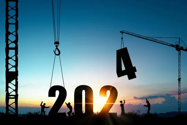 クレーンと曇りの青空の建設労働者のシルエット 歓迎された2024年新年パーティーの準備と新しいビジネスを変更する ストック写真