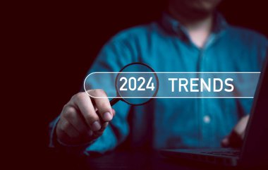 İş adamı elinde 2024 trendli büyüteç tutuyor. Pazarlama izleme ve iş planlama değişikliği kavramı için bar arıyor..