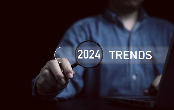 İş adamı elinde 2024 trendli büyüteç tutuyor. Pazarlama izleme ve iş planlama değişikliği kavramı için bar arıyor..