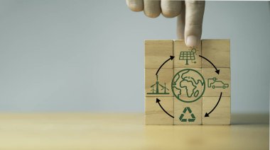 Hand holding wooden block cube with circle arrow environmental and earth icon for circular economy to sustainable development growth business earning profit and environment reservation concept. clipart