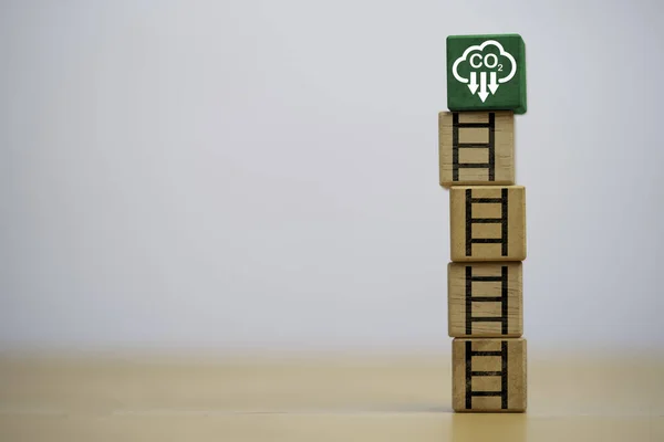 White reduction carbon emission symbol on the top of wooden block cube with staircase for carbon footprint and carbon credit to limit global warming from climate change by Circular Green Economy.