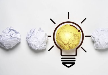 Yellow scrap paper ball with illustration painting among white paper for virtual lightbulb. It is creative different thinking idea for problem solving and innovation concept.	