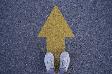 Sarı okla asfalt yolda duran koşucu devam et ve koşmaktan asla vazgeçme, iş ve yaşam tarzı kavramında kullanılacak..