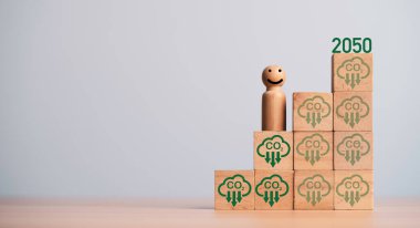 Miniature figure smile and standing on carbon reduction icon on wooden block cube for progressive of carbon credit footprint for carbon dioxide absorption to limit global warming within 2050 concept. clipart
