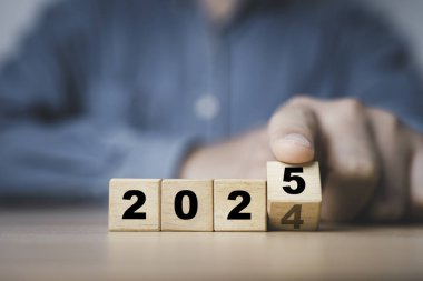 2024 'ten 2025' e kadar yeni yıl değişimine hazırlık için tahta blok küpü üzerinde çalışan işadamı yeni iş hedefi stratejisi kavramına başladı.