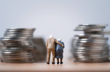 Zengin olmak için para biriktiren yaşlı çiftlerin minyatür figürü. Finansal planlama, para biriktirme ve emeklilik konseptinin hayat sigortası.. 