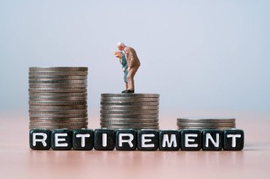 En üst madeni paraların üzerinde duran yaşlı çiftlerin minyatür figürleri. Emeklilik konseptinin finansal planlaması, para tasarrufu ve hayat sigortası için para biriktiriyorlar.. 