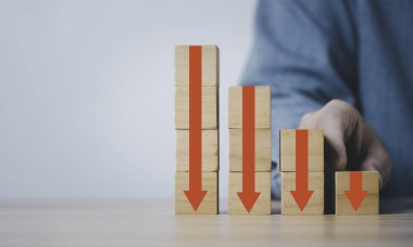 Elinde kırmızı ok tutan işadamı, ekranı tahta blok küp üzerine yazdırıyor ve maliyet kar ekonomisi ve fayda azaltma kavramı için alanı kopyalıyor..