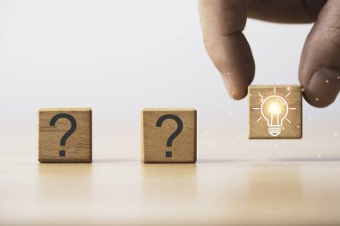 Yaratıcı düşünce ve problem çözme kavramı için soru işareti arasında parlayan ampulü tutmak.