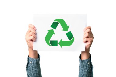 Eller, yeşil geri dönüşüm sembolünü gösteren beyaz bir kağıt tutuyordu. Arka plan düz beyaz, sürdürülebilirliğin ve çevresel bilincin önemini vurguluyor..