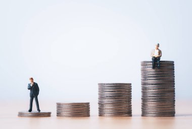 Minyatür şahsiyet genç işadamı ve emeklilik konseptinin zenginlik planlaması, para tasarrufu ve hayat sigortası için üst sikkelerde oturan kıdemli emekliler.. 