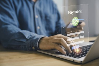 Çevrimiçi ödeme konseptini dijital işlem ile güvence altına almak, dizüstü bilgisayar ve akıllı telefon kullanan adamın kredi kartı bilgilerini girmesi, fintech, e-ticaret, güvenli internet bankacılık teknolojisi.