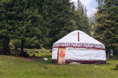 Yurt Jeti Oguz Vadisi 'nde. Kırgızistan ve Asya ülkelerinin eski ulusal evi. Yeşil çayırlar ve dağlık arazilerin arka planında yurtlar. Yurt kampı turistler için.