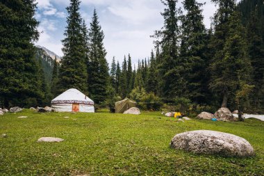 Yurt Jeti Oguz Vadisi 'nde. Kırgızistan ve Asya ülkelerinin eski ulusal evi. Yeşil çayırlar ve dağlık arazilerin arka planında yurtlar. Yurt kampı turistler için.