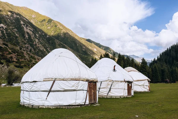 Yurt. Kırgızistan ve Asya ülkelerinin ulusal eski evi. Ulusal konut. Yeşil çayırlar ve dağlık arazilerin arka planında yurtlar. Yurt kampı turistler için.