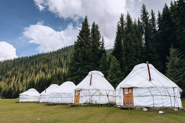 Yurt in Jeti Oğuz. Kırgızistan ve Asya ülkelerinin eski ulusal evi. Yeşil çayırlar ve dağlık arazilerin arka planında yurtlar. Yurt kampı turistler için.