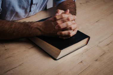 Adam, el ele tutuşup, el ele dua ediyor. Düşük ışık ortamında.