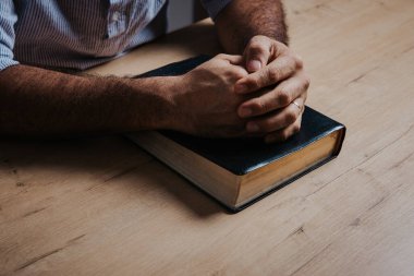 Adam, el ele tutuşup, el ele dua ediyor. Düşük ışık ortamında.