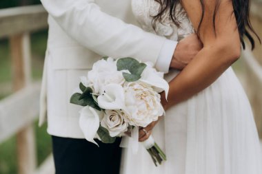 Yeni evli çiftin kucaklaşması. Gelinlerin elinde bir buket