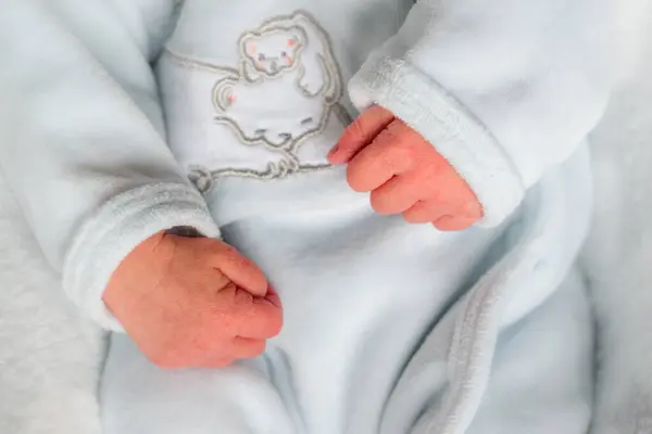 Close Van Een Hand Van Een Pasgeborene Met Witte Kleren Stockafbeelding