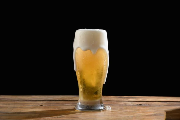 glass of cold light beer with foam on dark background