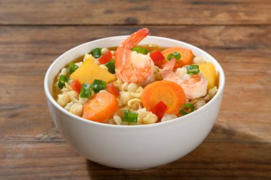 Karidesli lezzetli sebze çorbası, kırsal bir ahşap masada beyaz bir kase içinde.