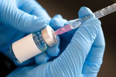 Doktorun elinde hastanede bir şırınga ve mavi bir aşı şişesi var. Sağlık ve tıbbi kavramlar