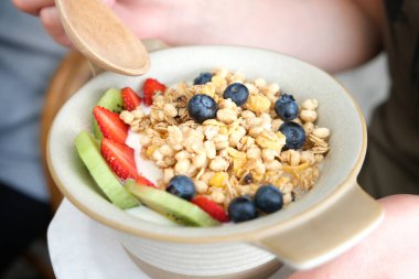 Kadının eli karışık meyve gevreği ve yoğurt sağlıklı yiyecek ve ağırlık yönetimi kavramı..