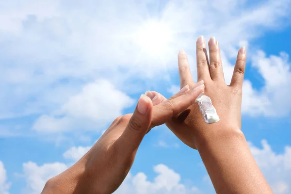 stock image Hand of female holding sunscreen. Very sun light Sky background.Health concepts and skin care