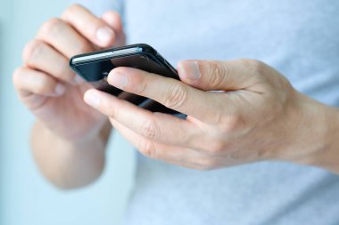 Genç adamın eli. Sosyal ağdaki arkadaşlarıyla bağlantı kurmak için akıllı telefon kullanıyor..