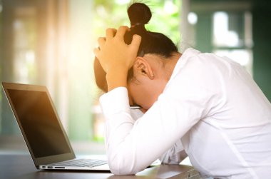 woman sitting down, his face unsettled. At the computer desk she has headaches and stress. Cause of hard work and insufficient rest.