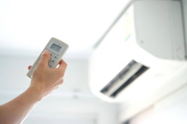 Adamın eli uzaktan kumanda ile açılıyor klima yatak odasında 25 santigrat dereceye kadar soğutuluyor. Sağlık kavramları ve enerji tasarrufları