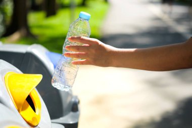 Lütfen plastik şişeyi depoya atın. Bir adam çöp tenekesine çöp atar gibi çöp atmak için çöpleri ayırır. ,